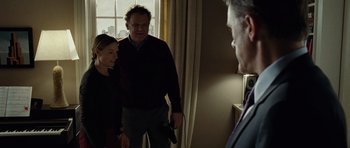 Movie still from “Carnage” (2011), directed by Roman Polanski – A man and a woman standing next to each other holding a gun; Medium shot, Over the shoulder angle