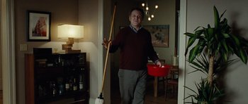 Movie still from “Carnage” (2011), directed by Roman Polanski – A man holding a mop and a bucket in a living room; Medium shot, Low angle