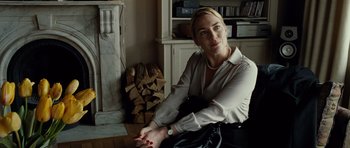 Movie still from “Carnage” (2011), directed by Roman Polanski – A woman sitting on the floor in front of a fireplace; Medium shot, Low angle