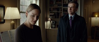 Movie still from “Carnage” (2011), directed by Roman Polanski – A man and a woman standing in front of a bookcase; Medium shot, Over the shoulder angle