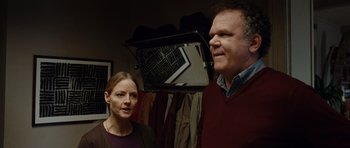 Movie still from “Carnage” (2011), directed by Roman Polanski – A man and a woman standing next to each other in a room; Medium shot, Over the shoulder angle
