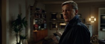Movie still from “Carnage” (2011), directed by Roman Polanski – A man standing in a living room looking at the camera; Medium shot, Over the shoulder angle