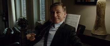 Movie still from “Carnage” (2011), directed by Roman Polanski – A man in a suit and tie holding a glass of wine; Medium shot, Low angle