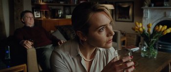 Movie still from “Carnage” (2011), directed by Roman Polanski – A woman sitting in front of a window holding a wine glass; Close Up shot, Over the shoulder angle