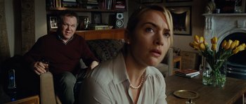Movie still from “Carnage” (2011), directed by Roman Polanski – A woman sitting in front of a man in a room; Medium shot, Over the shoulder angle