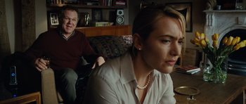 Movie still from “Carnage” (2011), directed by Roman Polanski – A woman sitting on a couch next to a man; Medium shot, Over the shoulder angle