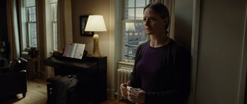 Movie still from “Carnage” (2011), directed by Roman Polanski – A woman standing in front of a window holding a nintendo wii game controller; Medium shot, Over the shoulder angle