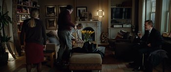 Movie still from “Carnage” (2011), directed by Roman Polanski – Two people standing in a living room near a fire place; Wide shot, Over the shoulder angle