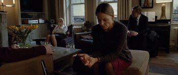Movie still from “Carnage” (2011), directed by Roman Polanski – A woman sitting on the floor looking at her cell phone; Medium shot, Over the shoulder angle