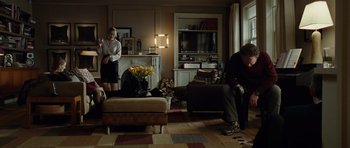 Movie still from “Carnage” (2011), directed by Roman Polanski – A man and a woman sitting on a couch in a living room; Wide shot, Over the shoulder angle