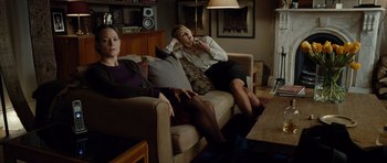 Movie still from “Carnage” (2011), directed by Roman Polanski – Two women sitting on a couch in a living room; Wide shot, High angle