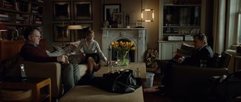 Movie still from “Carnage” (2011), directed by Roman Polanski – A woman sitting on top of a couch in a living room; Wide shot, Over the shoulder angle