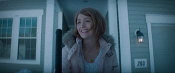 Movie still from “Spirited” (2022), directed by Sean Anders – A woman in a pink jacket smiling for the camera; Medium shot, Over the shoulder angle
