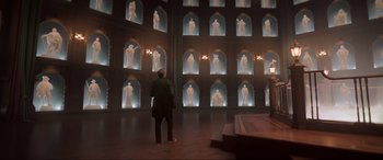 Movie still from “Spirited” (2022), directed by Sean Anders – A man standing in front of a wall of statues; Extreme Wide shot, Over the shoulder angle