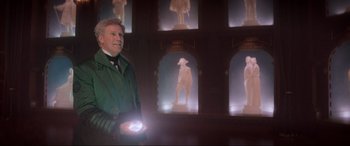 Movie still from “Spirited” (2022), directed by Sean Anders – A man holding a flashlight in front of a display of statues; Medium shot, Low angle
