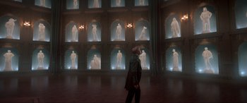 Movie still from “Spirited” (2022), directed by Sean Anders – A man standing in front of a wall of statues; Extreme Wide shot, Low angle