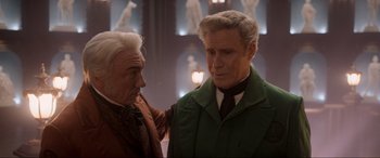 Movie still from “Spirited” (2022), directed by Sean Anders – A man in a green jacket standing next to another man in a brown jacket; Medium shot, Over the shoulder angle