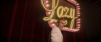 Movie still from “Spirited” (2022), directed by Sean Anders – A man standing in front of a neon sign; Medium shot, Low angle