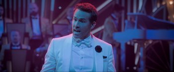 Movie still from “Spirited” (2022), directed by Sean Anders – A man in a white suit and a bow tie; Close Up shot, Over the shoulder angle