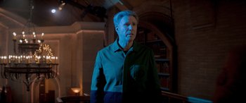 Movie still from “Spirited” (2022), directed by Sean Anders – A man standing in front of a bookshelf in a room; Medium shot, Low angle