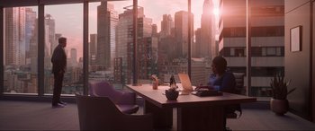 Movie still from “Spirited” (2022), directed by Sean Anders – A woman sitting at a table with a laptop in front of a large window; Extreme Wide shot, High angle