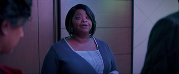 Movie still from “Spirited” (2022), directed by Sean Anders – A woman with short black hair is standing in front of a wall; Medium shot, Low angle