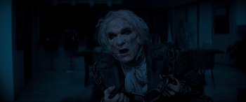 Movie still from “Spirited” (2022), directed by Sean Anders – An old man is chained to a metal chain; Close Up shot, High angle