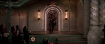 Movie still from “Spirited” (2022), directed by Sean Anders – A man standing in front of an entrance to a building; Wide shot, Low angle