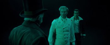 Movie still from “Spirited” (2022), directed by Sean Anders – A man in a suit and tie standing next to another man in a suit and tie; Medium shot, Over the shoulder angle