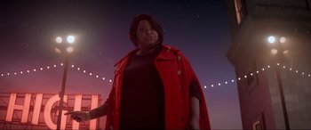 Movie still from “Spirited” (2022), directed by Sean Anders – A woman in a red coat standing in front of a street light at night; Medium shot, Low angle