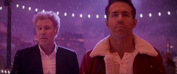 Movie still from “Spirited” (2022), directed by Sean Anders – Two men standing next to each other in front of lights; Medium shot, Over the shoulder angle