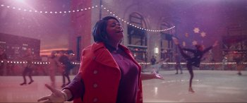 Movie still from “Spirited” (2022), directed by Sean Anders – A woman in a red coat standing on a street; Medium shot, Low angle