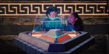 Movie still from “Spy Kids: Armageddon” (2023), directed by Robert Rodriguez – Two people looking at a display of a pyramid; Medium shot, High angle