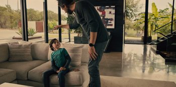 Movie still from “Spy Kids: Armageddon” (2023), directed by Robert Rodriguez – A man and a boy playing a video game on the couch; Medium shot, Over the shoulder angle