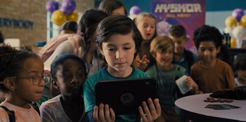 Movie still from “Spy Kids: Armageddon” (2023), directed by Robert Rodriguez – A group of children looking at a tablet; Medium shot, High angle