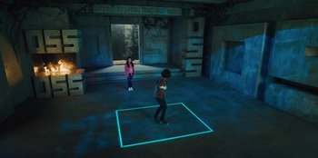 Movie still from “Spy Kids: Armageddon” (2023), directed by Robert Rodriguez – Two children are standing in a dark room; Extreme Wide shot, High angle