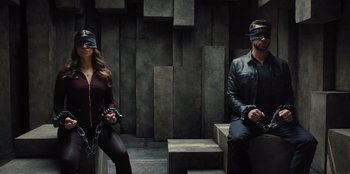Movie still from “Spy Kids: Armageddon” (2023), directed by Robert Rodriguez – A man and a woman wearing blindfolds and sitting on steps; Wide shot, High angle