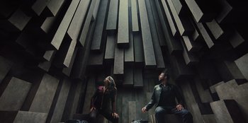Movie still from “Spy Kids: Armageddon” (2023), directed by Robert Rodriguez – A man and a woman sitting in front of a wall; Wide shot, Overhead angle
