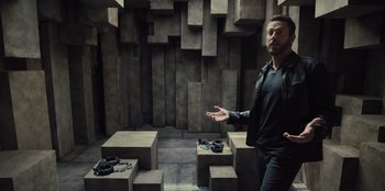 Movie still from “Spy Kids: Armageddon” (2023), directed by Robert Rodriguez – A man standing in front of a wall with a bunch of shoes; Wide shot, High angle