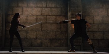 Movie still from “Spy Kids: Armageddon” (2023), directed by Robert Rodriguez – A man holding a sword in front of a brick wall; Wide shot, Low angle