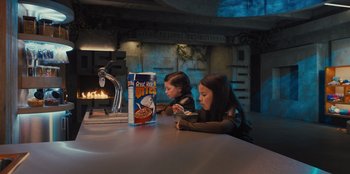 Movie still from “Spy Kids: Armageddon” (2023), directed by Robert Rodriguez – Two little girls sitting at a table with a box of cereal; Medium shot, High angle