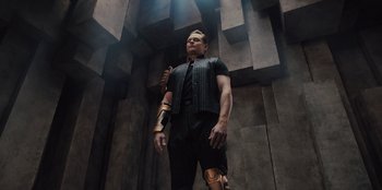 Movie still from “Spy Kids: Armageddon” (2023), directed by Robert Rodriguez – A man in a black shirt and a gold arm; Medium shot, Low angle