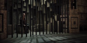 Movie still from “Spy Kids: Armageddon” (2023), directed by Robert Rodriguez – A woman sitting on a chair in front of a metal fence; Wide shot, High angle