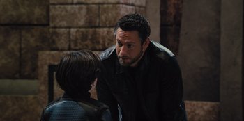 Movie still from “Spy Kids: Armageddon” (2023), directed by Robert Rodriguez – A man talking to a young boy in front of a brick wall; Close Up shot, Over the shoulder angle