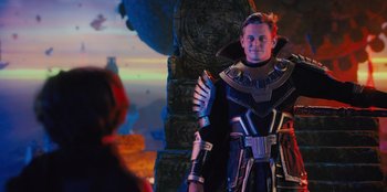 Movie still from “Spy Kids: Armageddon” (2023), directed by Robert Rodriguez – A man dressed in a costume standing in front of a statue; Medium shot, Over the shoulder angle