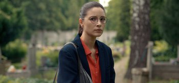 Movie still from “Squared Love Everlasting” (2023), directed by Filip Zylber – A woman wearing glasses and a blue jacket; Close Up shot, Over the shoulder angle
