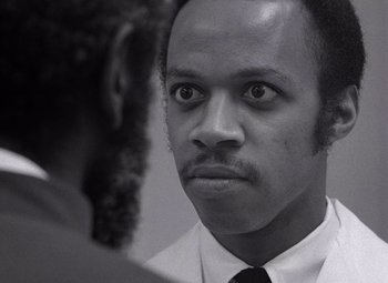 A black and white photo of a man looking at the camera