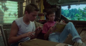 Movie still from “Stand by Me” (1986), directed by Rob Reiner – Two young boys sitting at a table looking at a book; Medium shot, High angle