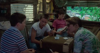 Movie still from “Stand by Me” (1986), directed by Rob Reiner – A group of young people sitting around a box; Medium shot, High angle