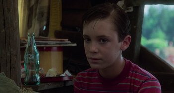 Movie still from “Stand by Me” (1986), directed by Rob Reiner – A young boy is sitting in front of a pile of papers; Close Up shot, Over the shoulder angle